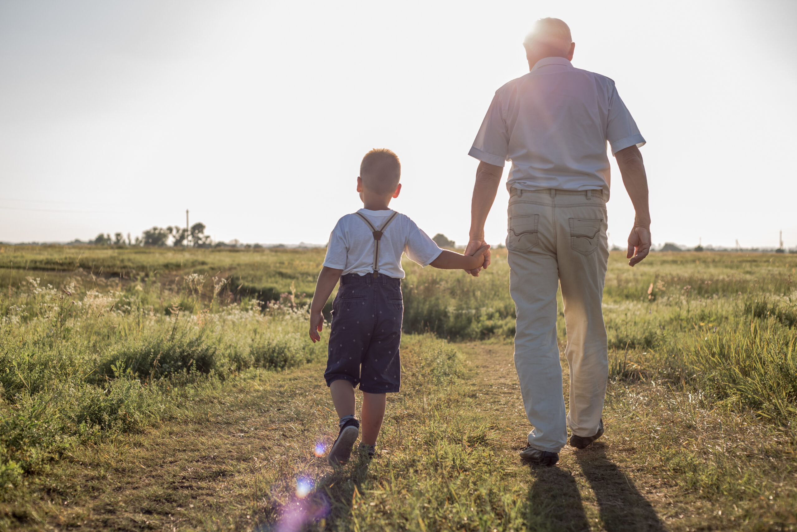 Homme et petit garçon qui marchent vers le soleil